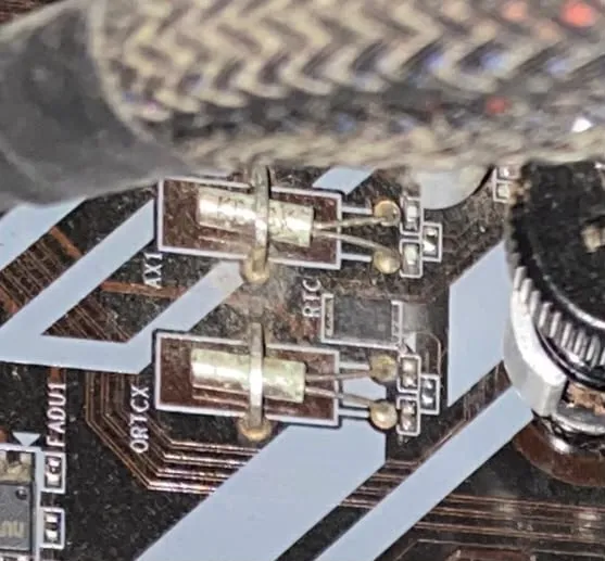 Close-up of two cylindrical metal-can crystal oscillators soldered to the motherboard, both visibly tarnished and discoloured, with corrosion around their solder joints. Silkscreen labels AX1 and RTC are visible on the board next to them.